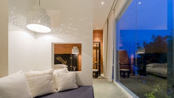 Een moderne slaapkamer met een groot raam, een bed met witte beddengoed en een wandlamp.