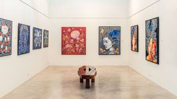 An art gallery with paintings on the walls and a wooden bench in the center.