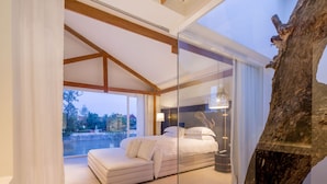 Un dormitorio moderno con una cama grande, un sofá y vistas a un cuerpo de agua.