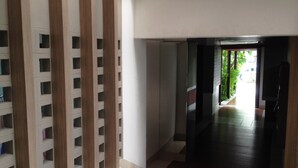 A hallway with a wooden partition and a view of a garden. - PT Court (Bangkok)