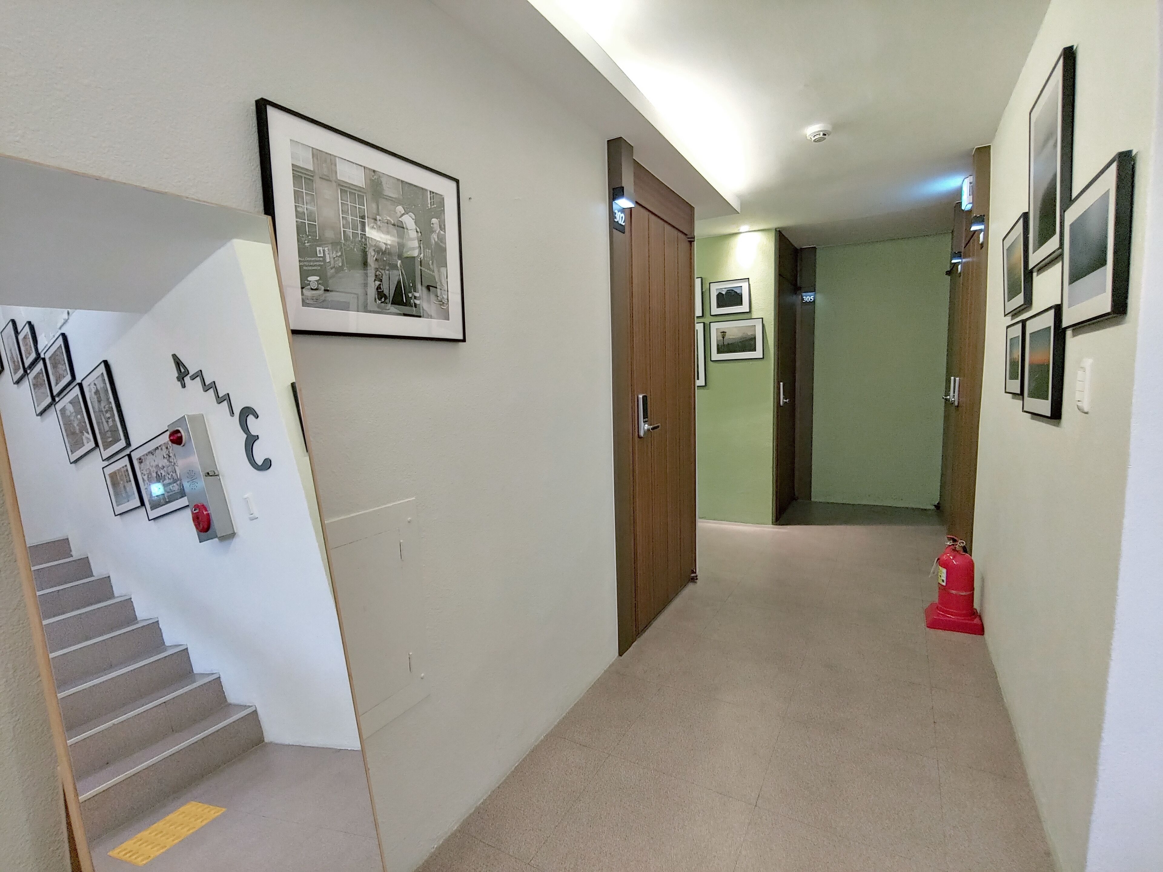 A hallway with a staircase, a fire extinguisher, and a door.