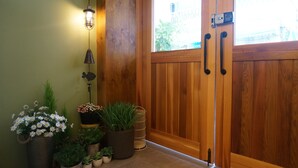 Une porte en bois avec une poignée, une plante en pot et un luminaire fixé au mur.