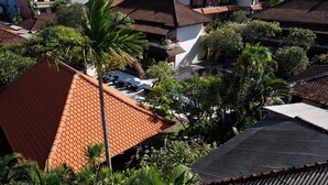 Un barrio residencial con varias casas, algunas con techos de tejas y otras con techos de lámina corrugada. Se ven palmeras y otra vegetación.