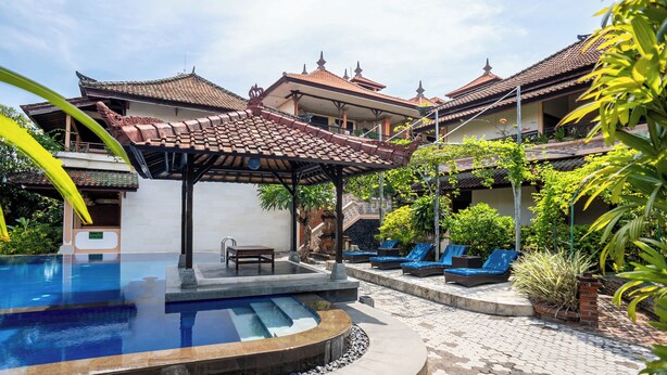 Una piscina con pérgola, sillones de descanso y arquitectura tradicional.