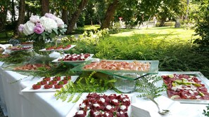 An outdoor buffet with various food items and a garden setting. - Villa Revedin (Gorgo al Monticano)