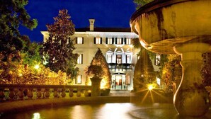A well-lit building with a fountain in the foreground, surrounded by trees and a stone balustrade. - Villa Revedin (Gorgo al Monticano)