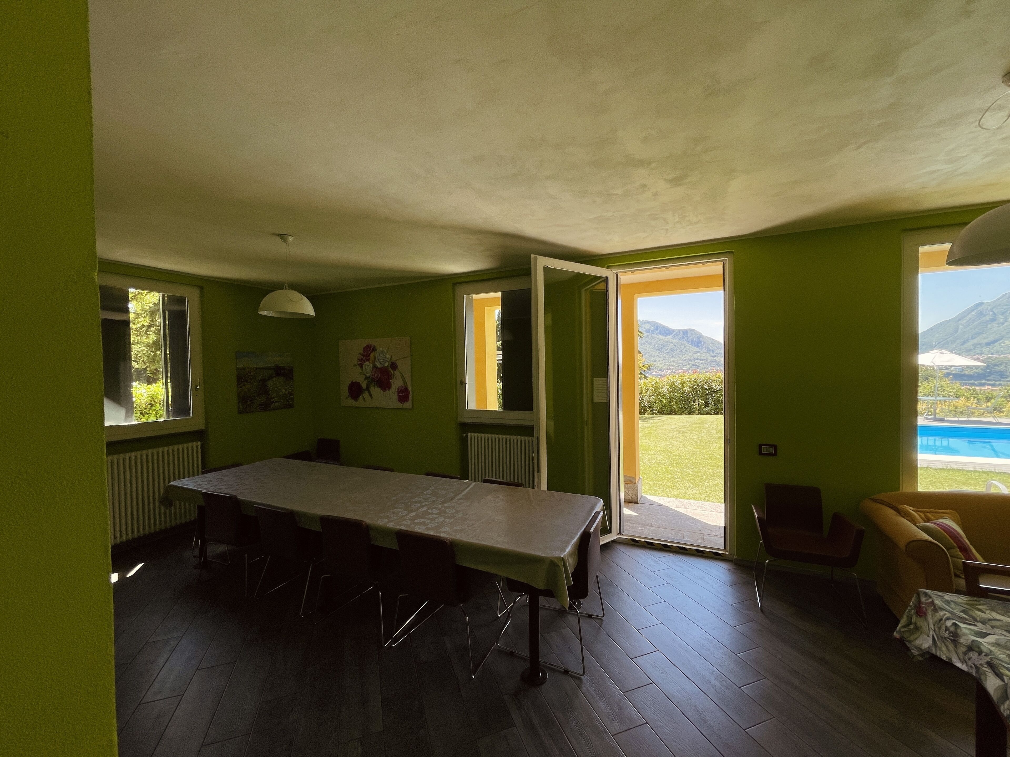 Ein Zimmer mit großem Tisch, einer Couch und Blick auf einen Berg und Pool.