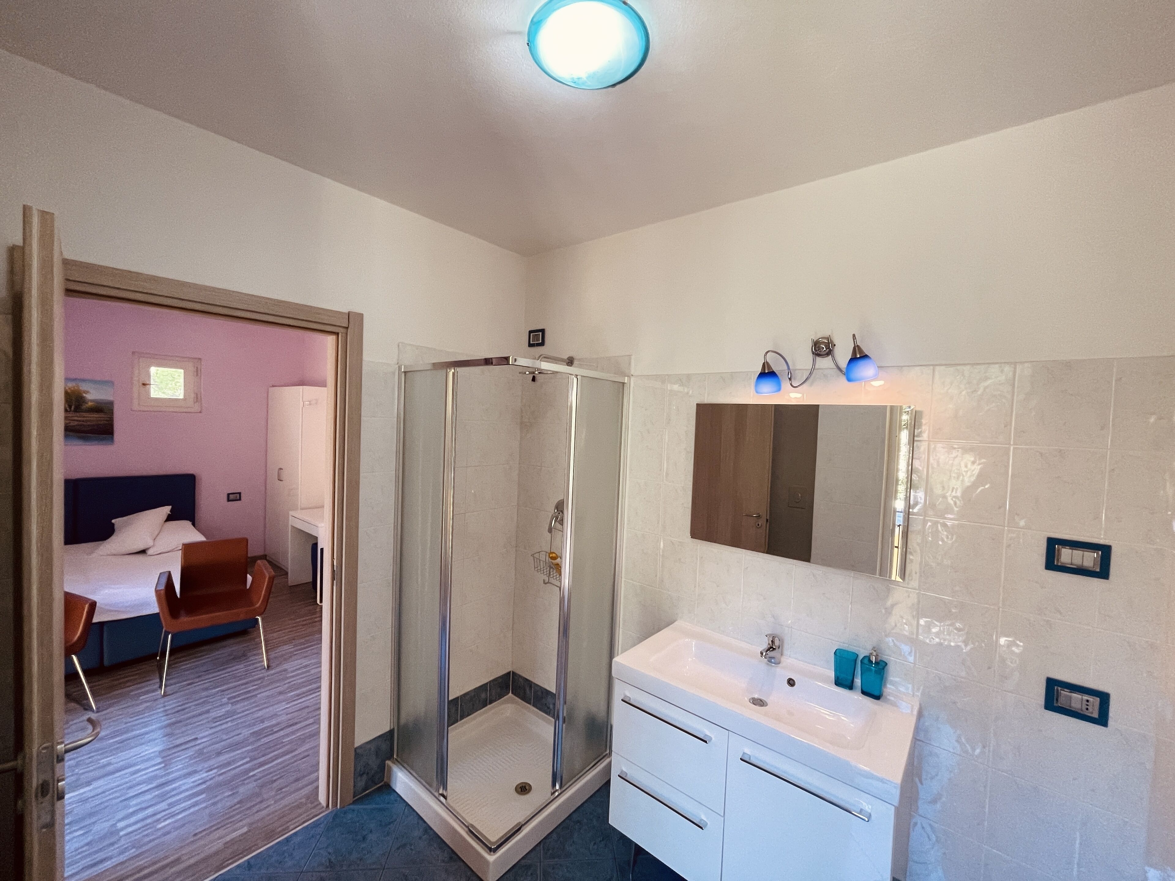 Habitación de hotel con ducha, cama, escritorio y silla.