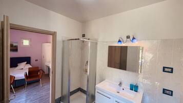 Habitación de hotel con ducha, cama, escritorio y silla.