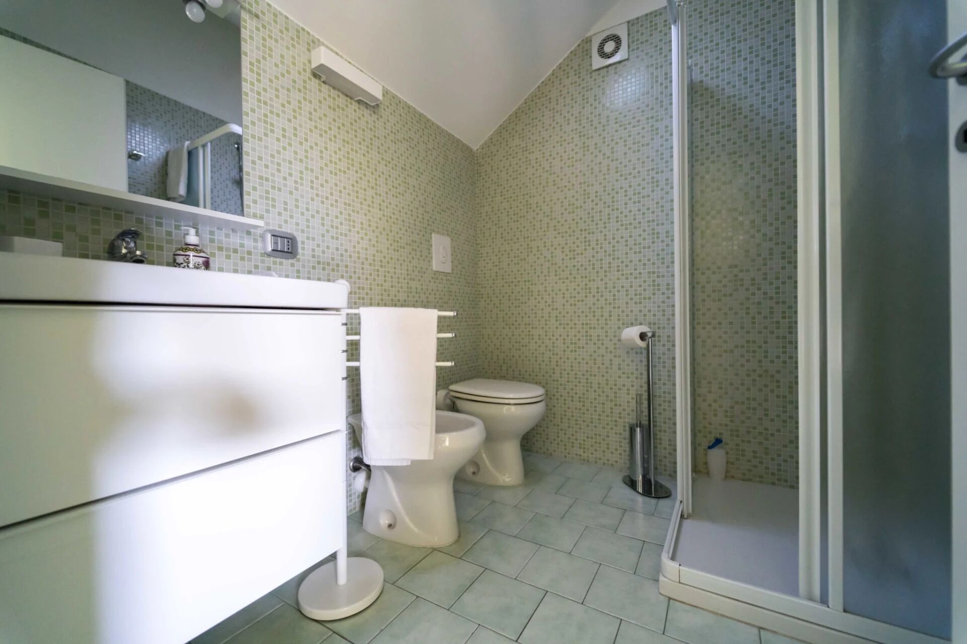 Een badkamer met toilet, wastafel en douche.