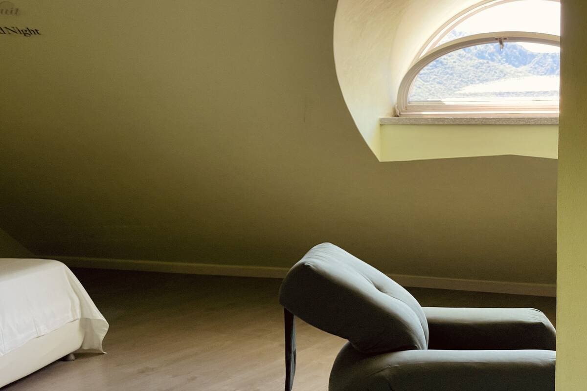 A bedroom with a single bed, a chair, and a window with a view of a snowy landscape.