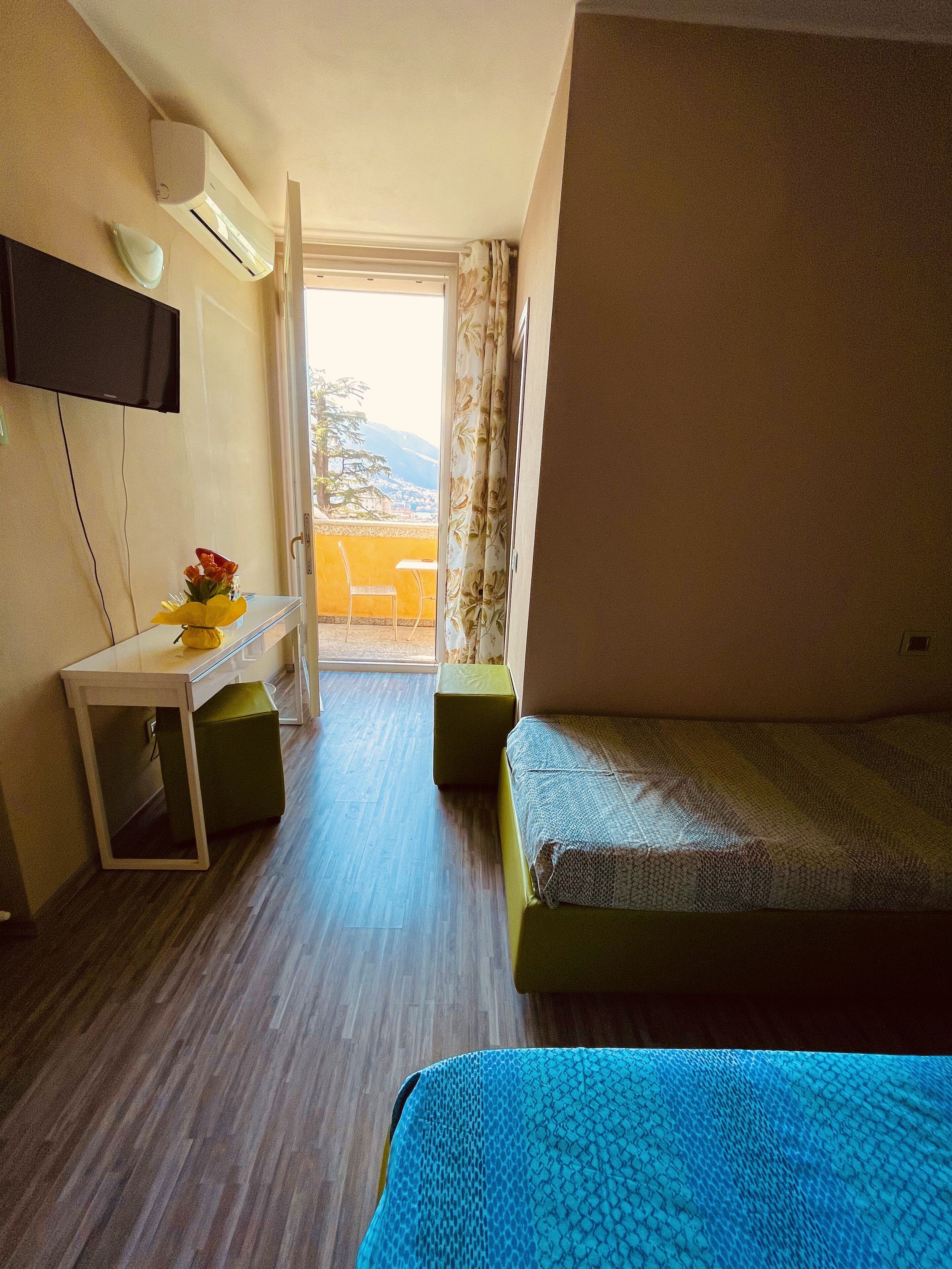 Ein Hotelzimmer mit Bett, Schreibtisch, Stuhl und Blick ins Freie.