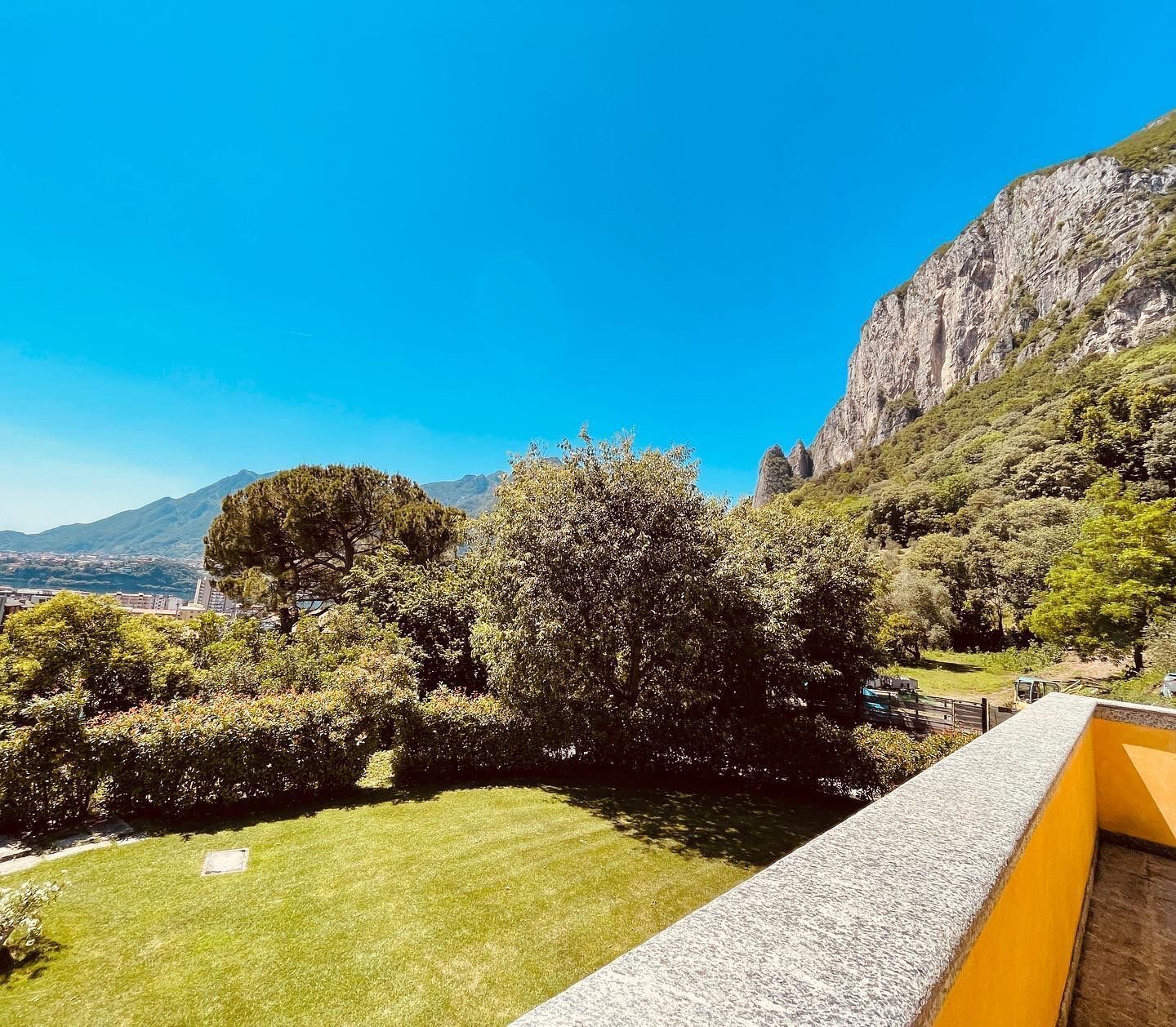 Une vue d’une pelouse verdoyante et luxuriante, avec une montagne en arrière-plan et un ciel bleu dégagé.