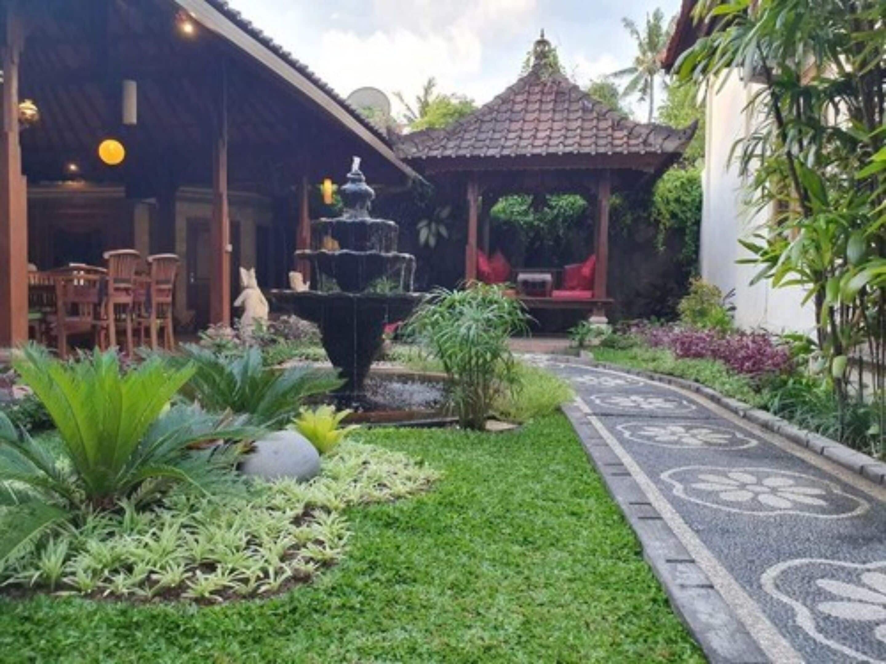 A garden with a fountain, a gazebo, and a pathway.