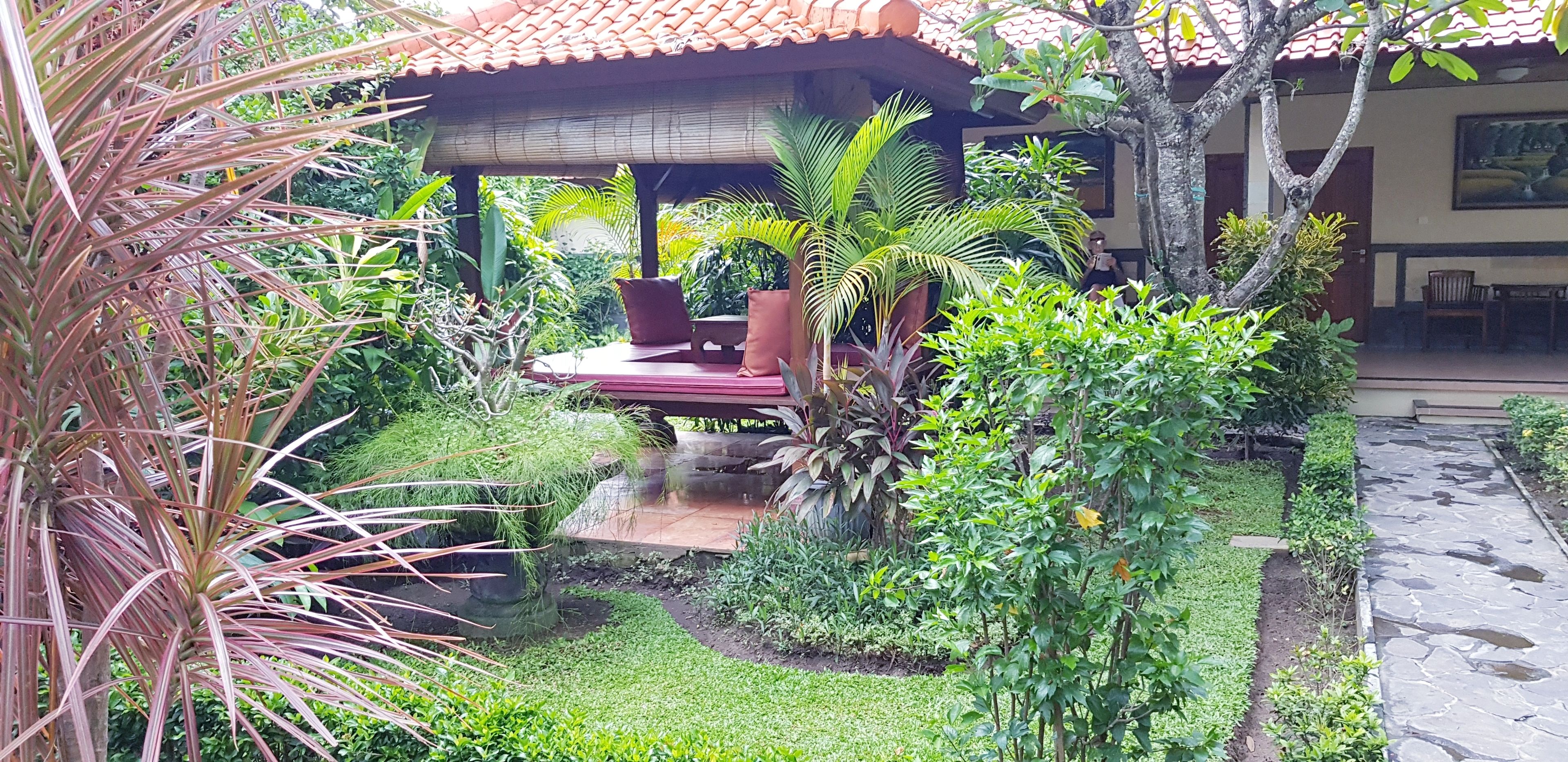 A garden with a patio area, a small water feature, and various plants.