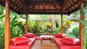 A wooden gazebo with a thatched roof, surrounded by lush tropical plants. - Kusnadi Hotel (Legian)