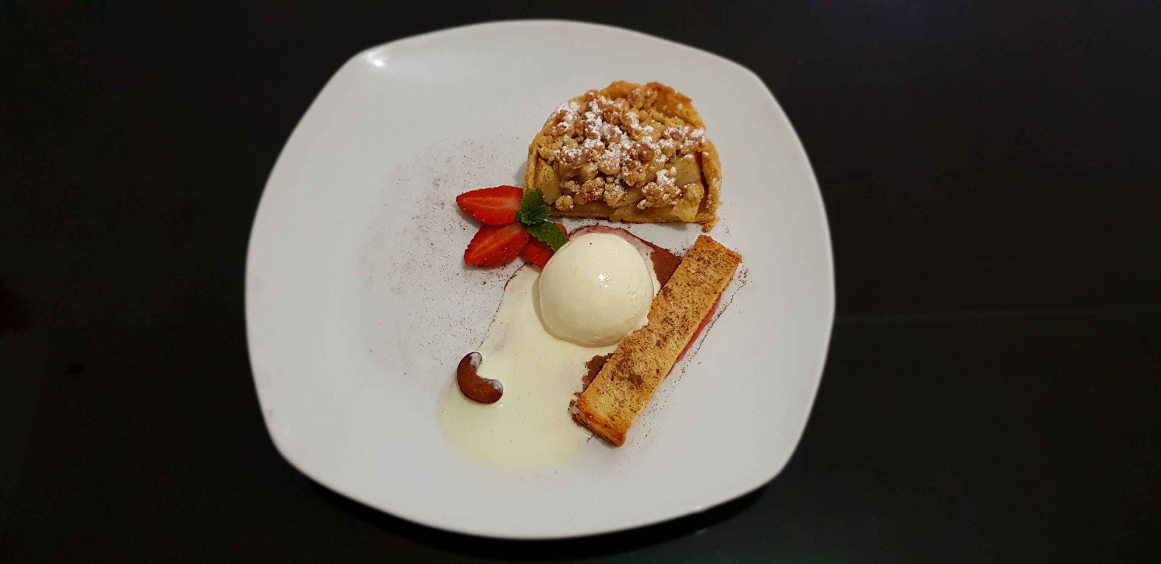 A dessert plate with a pastry, strawberries, a scoop of ice cream, and a piece of cake.