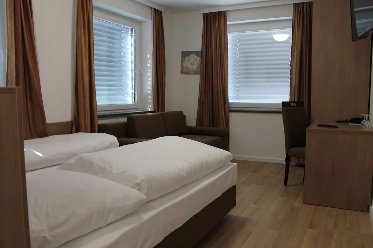 Une chambre d’hôtel avec deux lits, un bureau et une chaise.