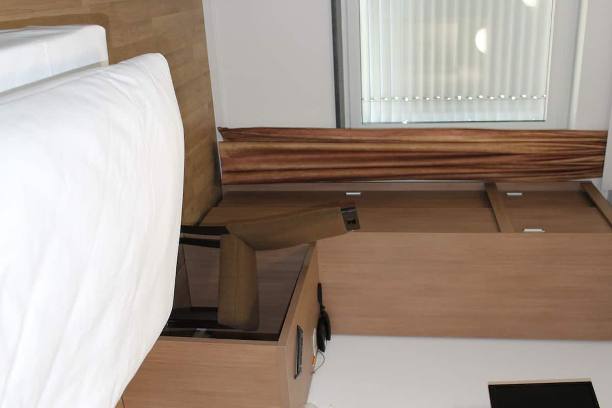 Un intérieur de camping-car compact et moderne, comprenant un lit, une petite table et une fenêtre avec des stores.