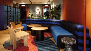 Un área de descanso moderna con un sofá modular azul y negro, una mesa de madera y una mesita redonda.