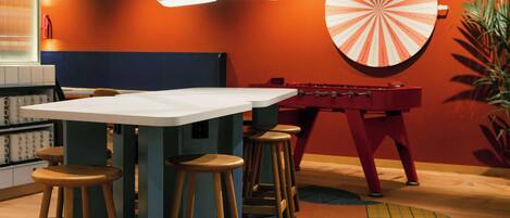Un área de bar con taburetes, una mesa de fútbol de mesa y un dardo.