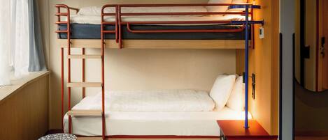 A bunk bed room with a wooden floor, a small table, and a red nightstand.