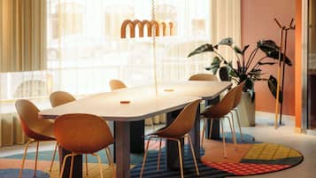 Un comedor moderno con una mesa larga y seis sillas, una lámpara colgante y un ventanal con cortinas.