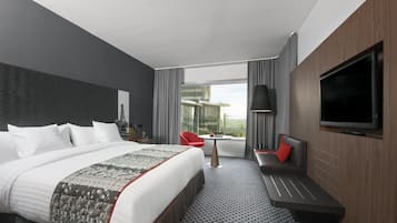 Une chambre d’hôtel moderne dotée d’un grand lit, d’un coin salon, d’une télévision et offrant une vue sur la ville.