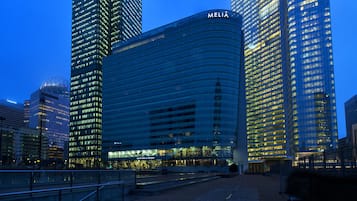 Ein modernes Hochhaus mit der Aufschrift "MELIA" auf der Fassade, umgeben von anderen hohen Gebäuden.