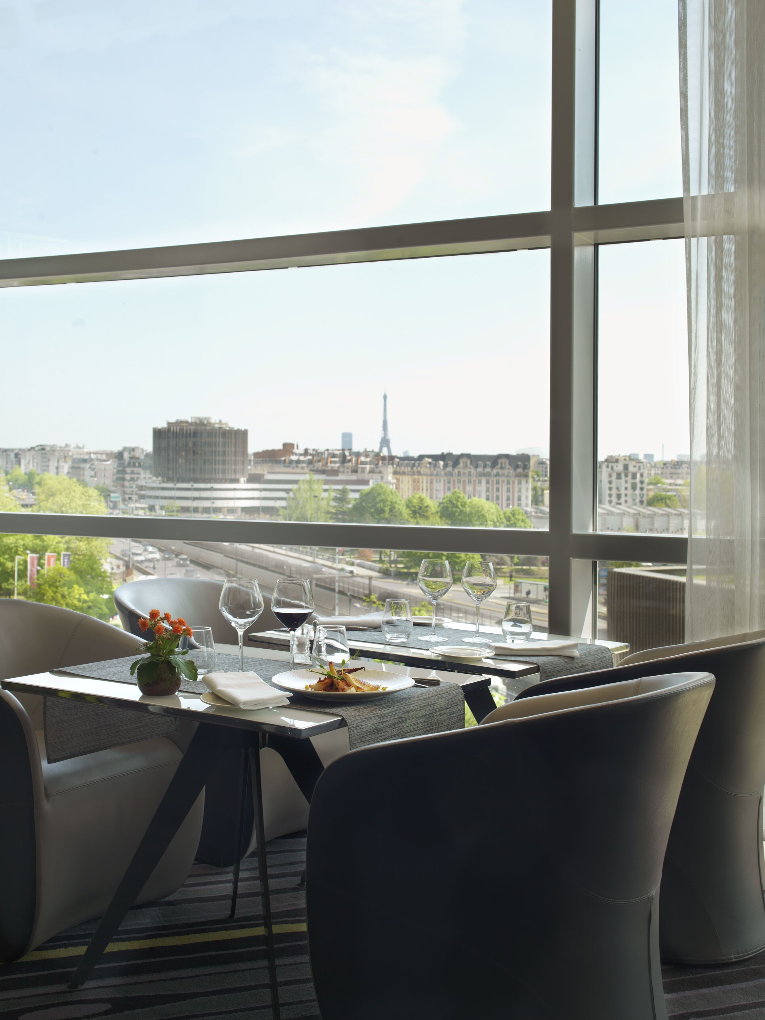 A dining table with chairs, a vase of flowers, and wine glasses set for a meal.