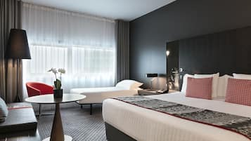 A hotel room with a large bed, a sofa, a small table, and a chair.