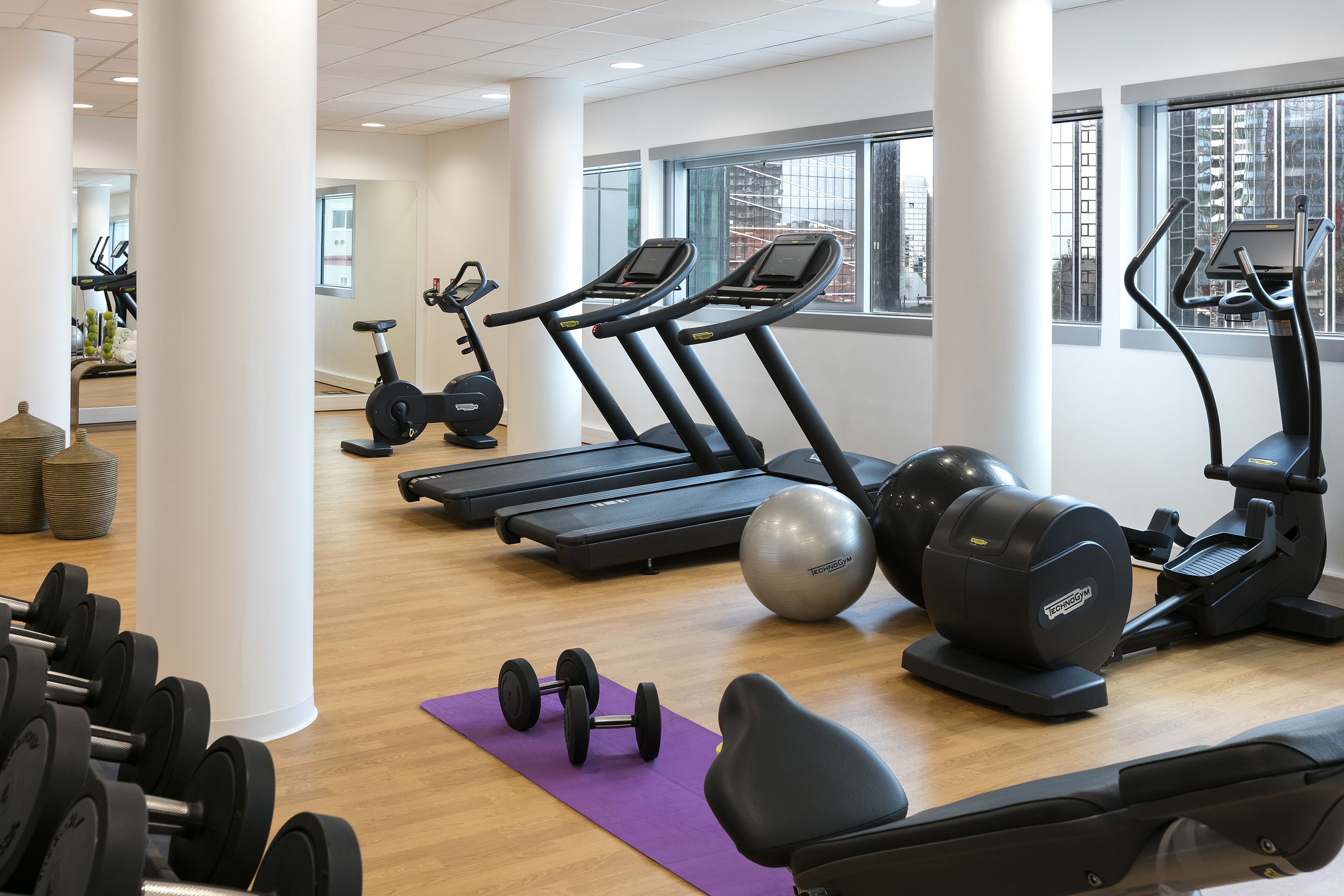 A gym with treadmills, an elliptical, dumbbells, and exercise balls.