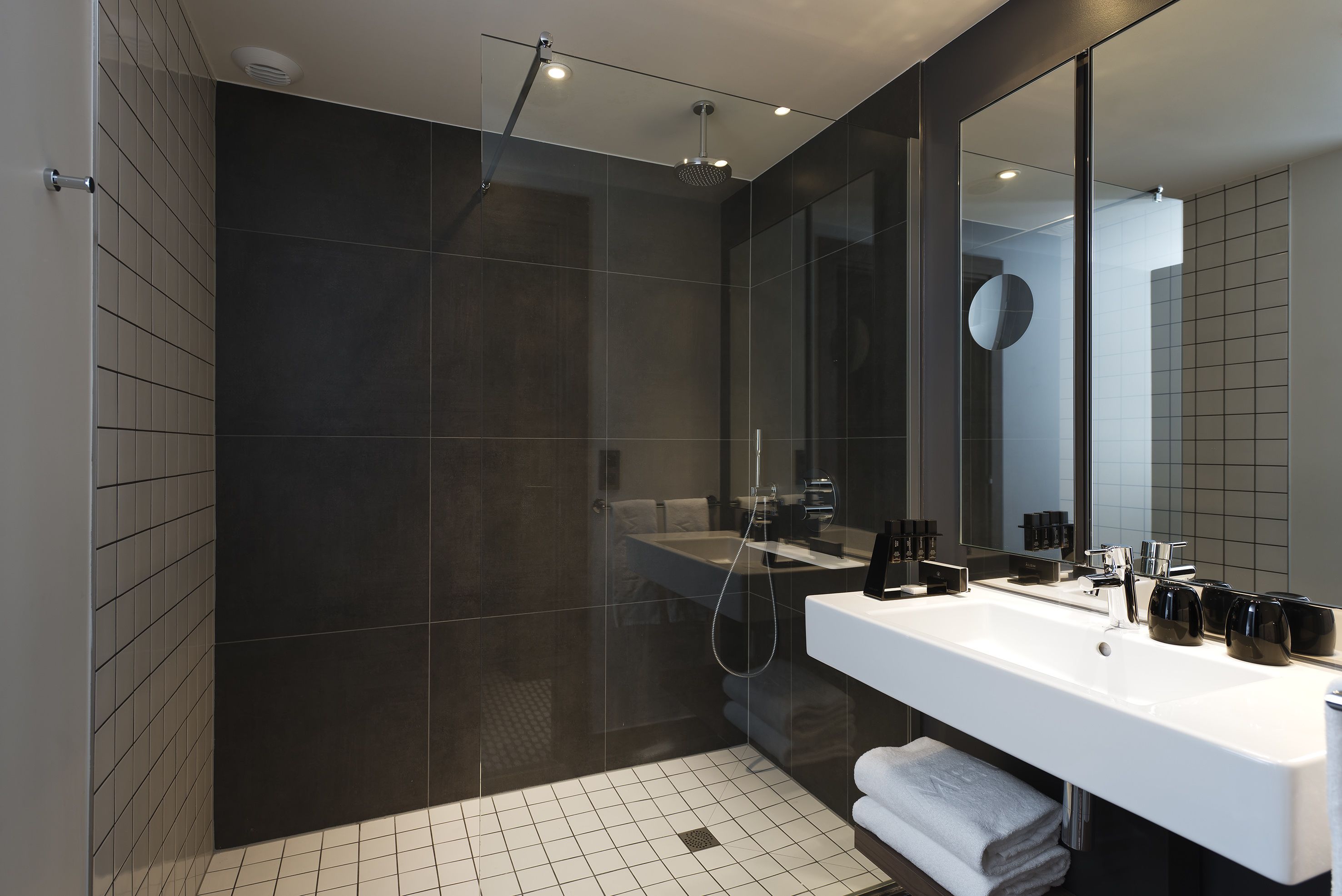 Un baño moderno con un espejo grande, un lavabo blanco y zona de ducha.