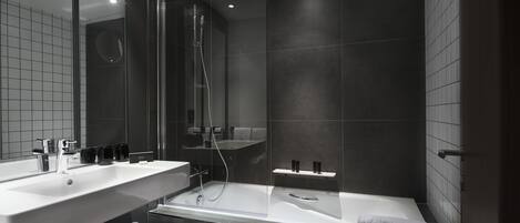 Un baño moderno con dos lavamanos, una bañera y zona de ducha con mampara de vidrio.