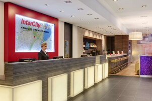Ein moderner Hotelbereich mit Empfangstresen, einer digitalen Kartenanzeige und einer Bar-Lounge-Ecke.