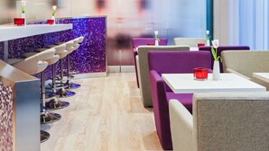 Un restaurante moderno con asientos de bar y cabinas moradas.