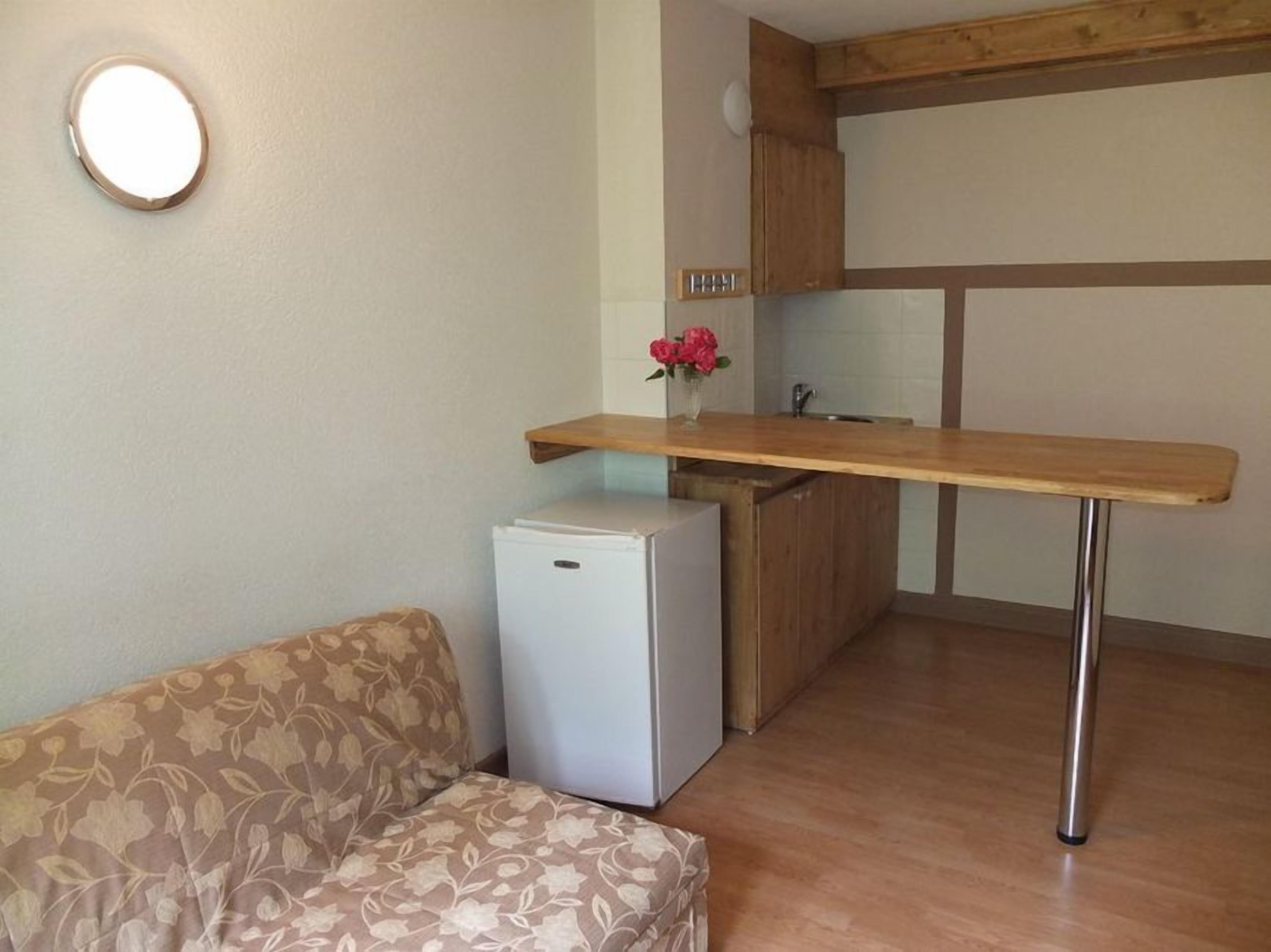 A compact kitchenette with a wooden countertop, a small refrigerator, and a sink.