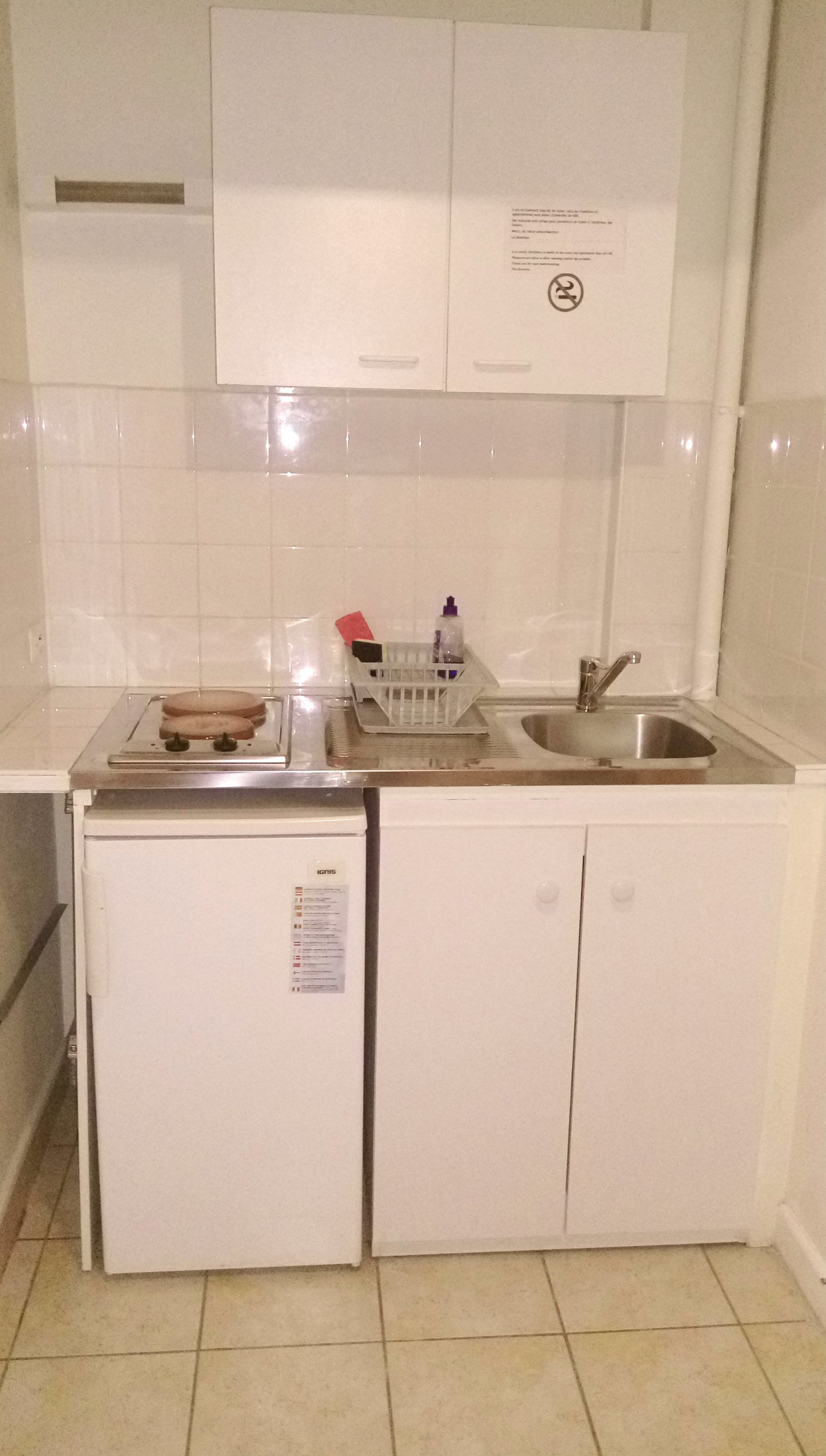 Uma cozinha compacta com geladeira, pia e um balcão pequeno.