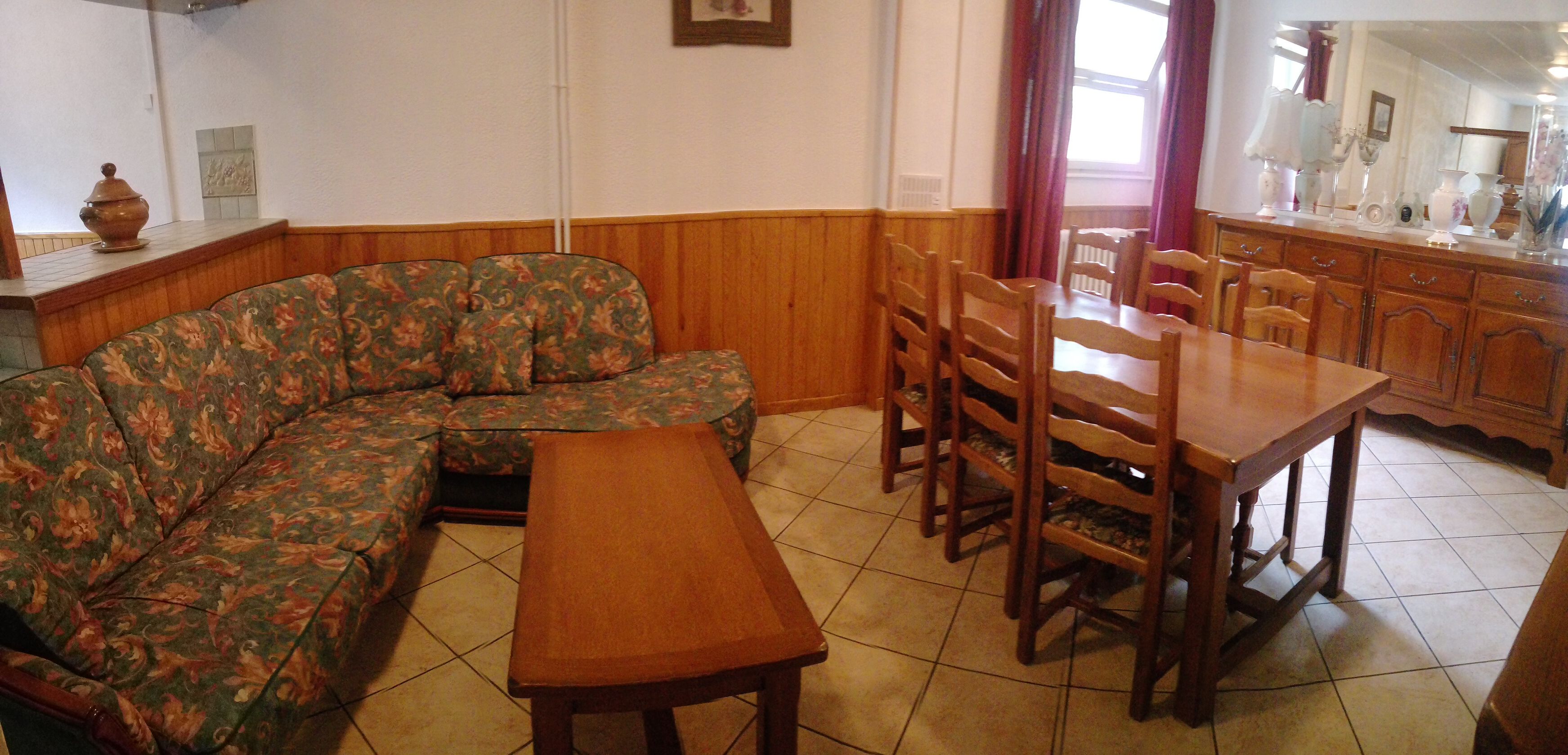 Una sala de estar con sofá, mesa de comedor de madera y sillas.