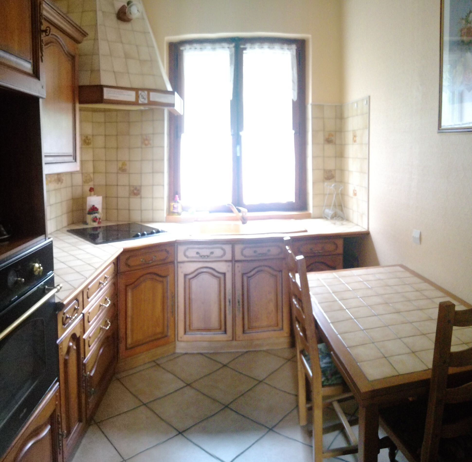 A kitchen with wooden cabinets, a tiled backsplash, a window with curtains, and a tiled floor.
