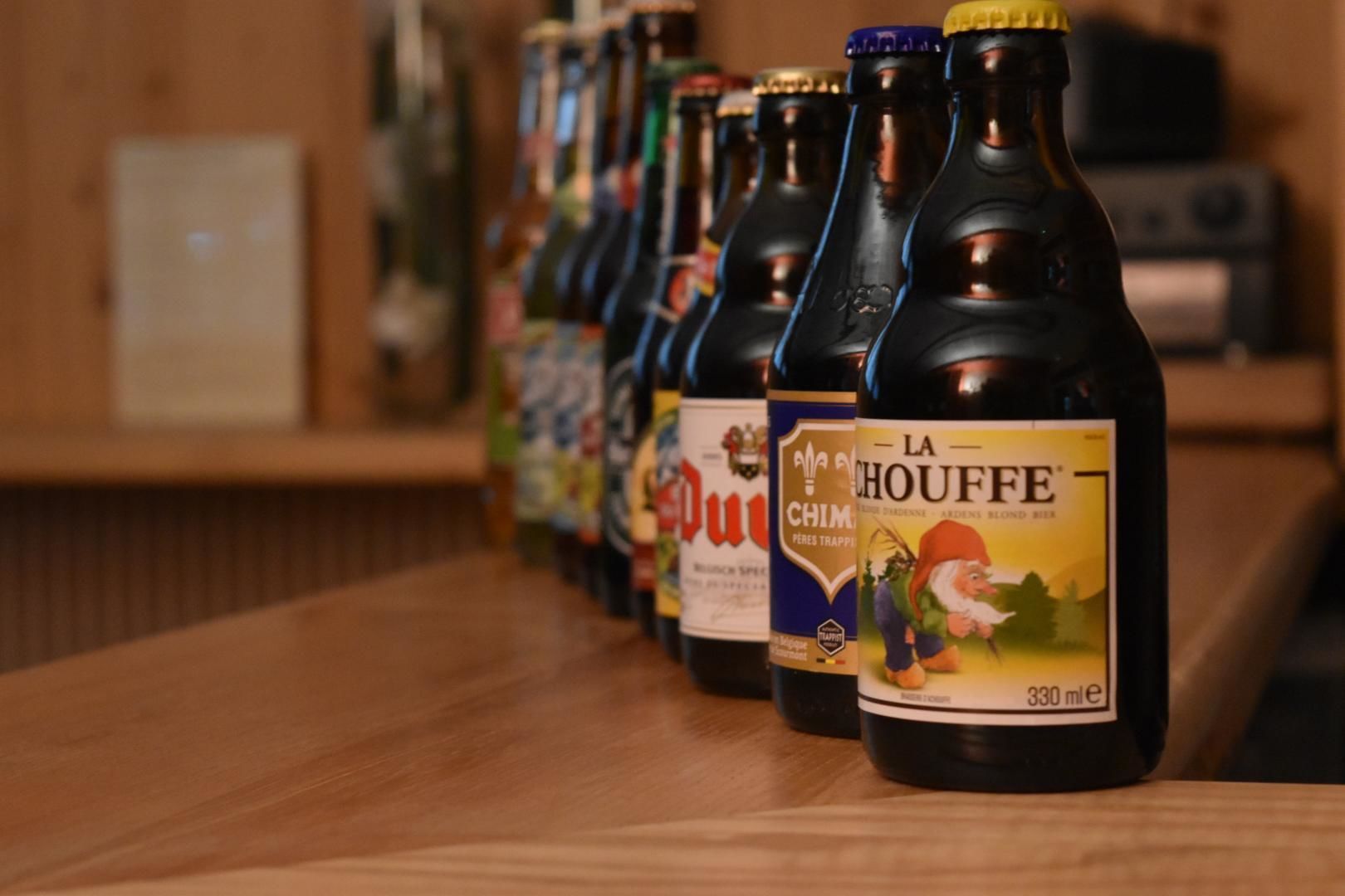 Une rangée de bouteilles de bière sur un comptoir en bois.