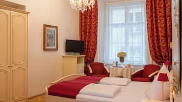 Una camera d'albergo con un letto, un comodino con una lampada, una televisione, un armadio e un'ampia finestra con tende.