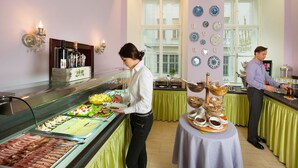 A buffet setup with various food items and a person serving.
