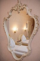 A room with two beds, a mirror, and wall sconces.