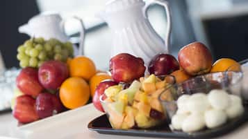 A fruit platter with apples, oranges, grapes, and melon on a tray.