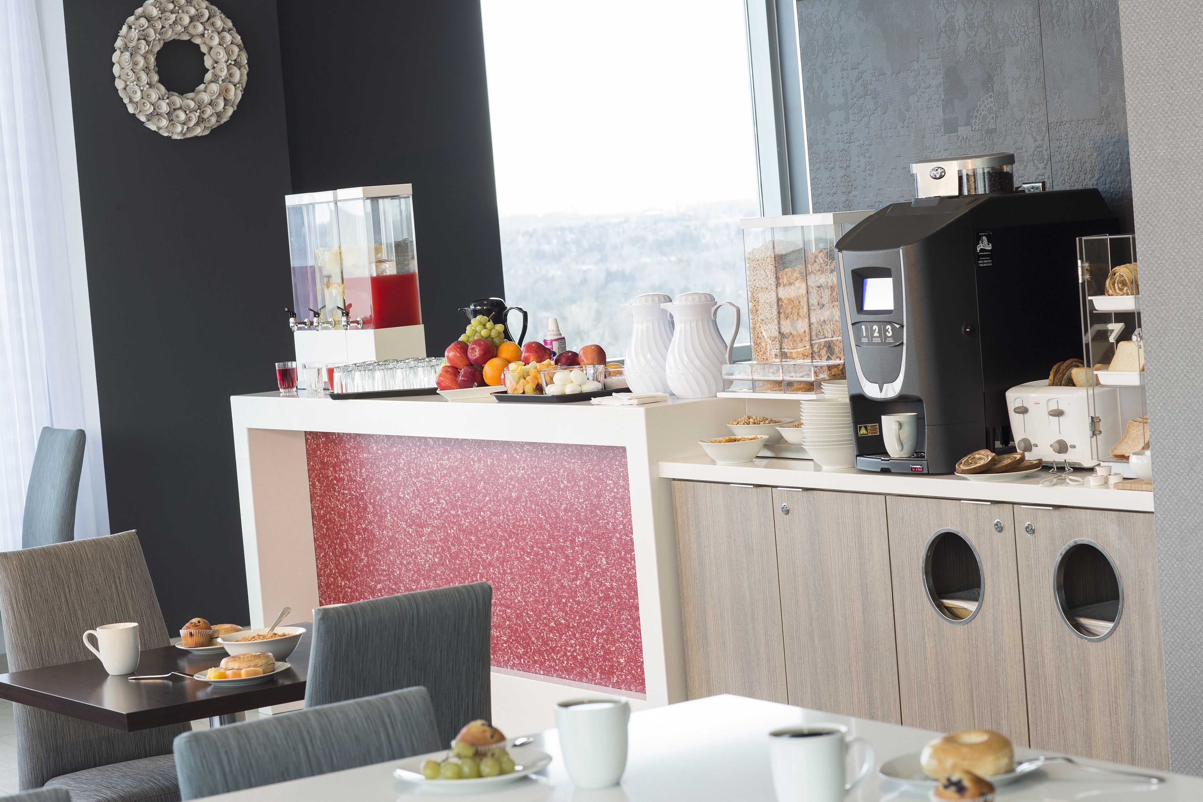 Un área de desayuno moderna con una cafetera, frutero y asientos.