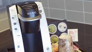 Una cafetera Keurig con una bandeja de goteo, un portacapsulas de café y una taza reutilizable.