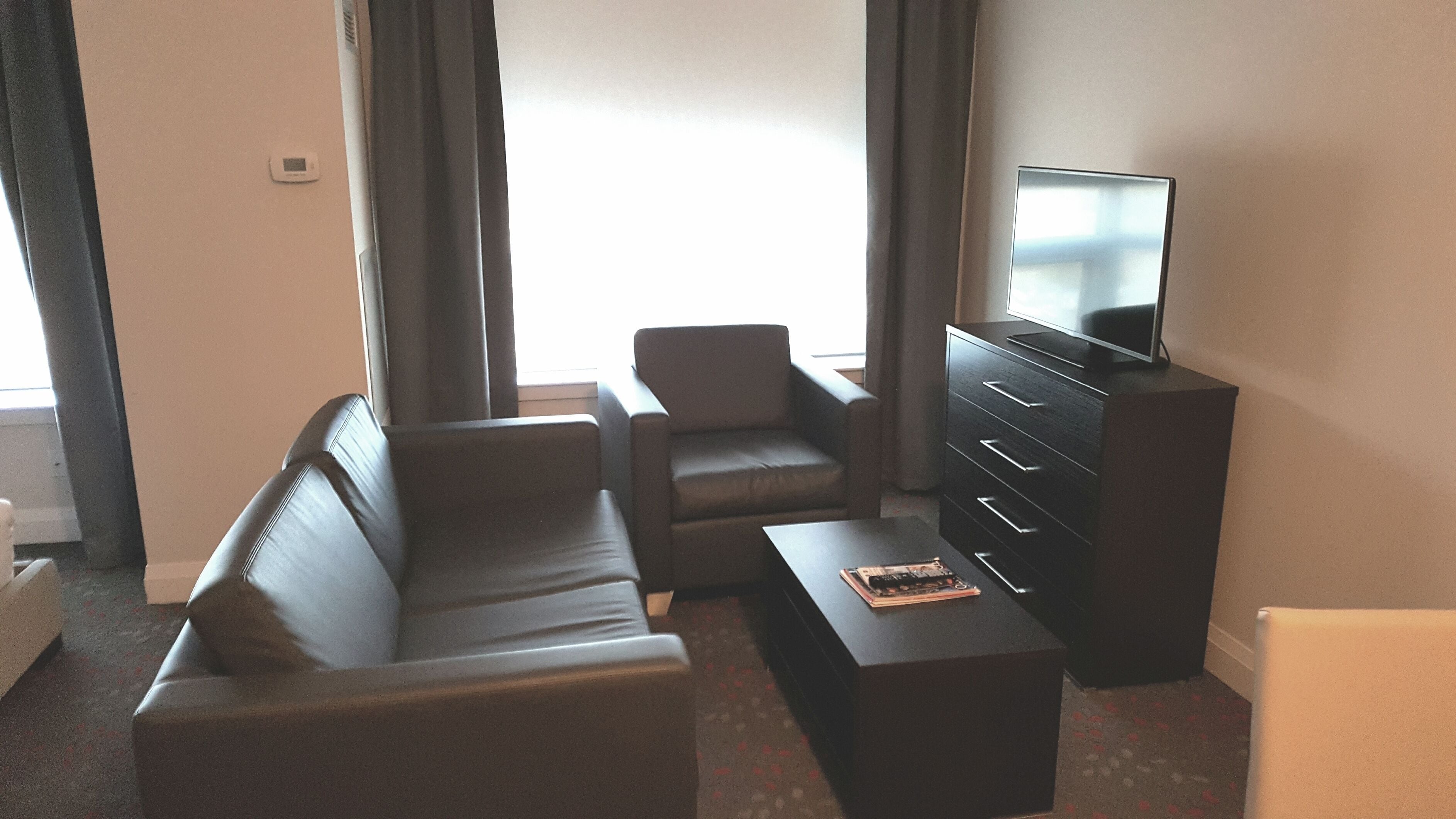 Una sala de estar moderna con un sofá, un sillón, una mesa de centro y un televisor sobre un mueble.