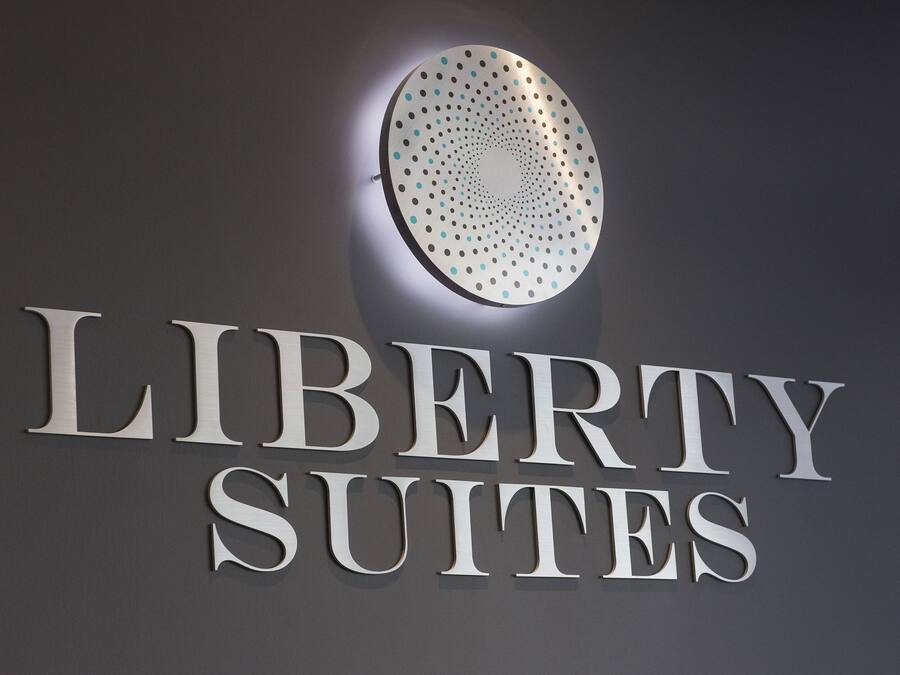 Letrero de 'LIBERTY SUITES' con un diseño circular y una lámpara encima.