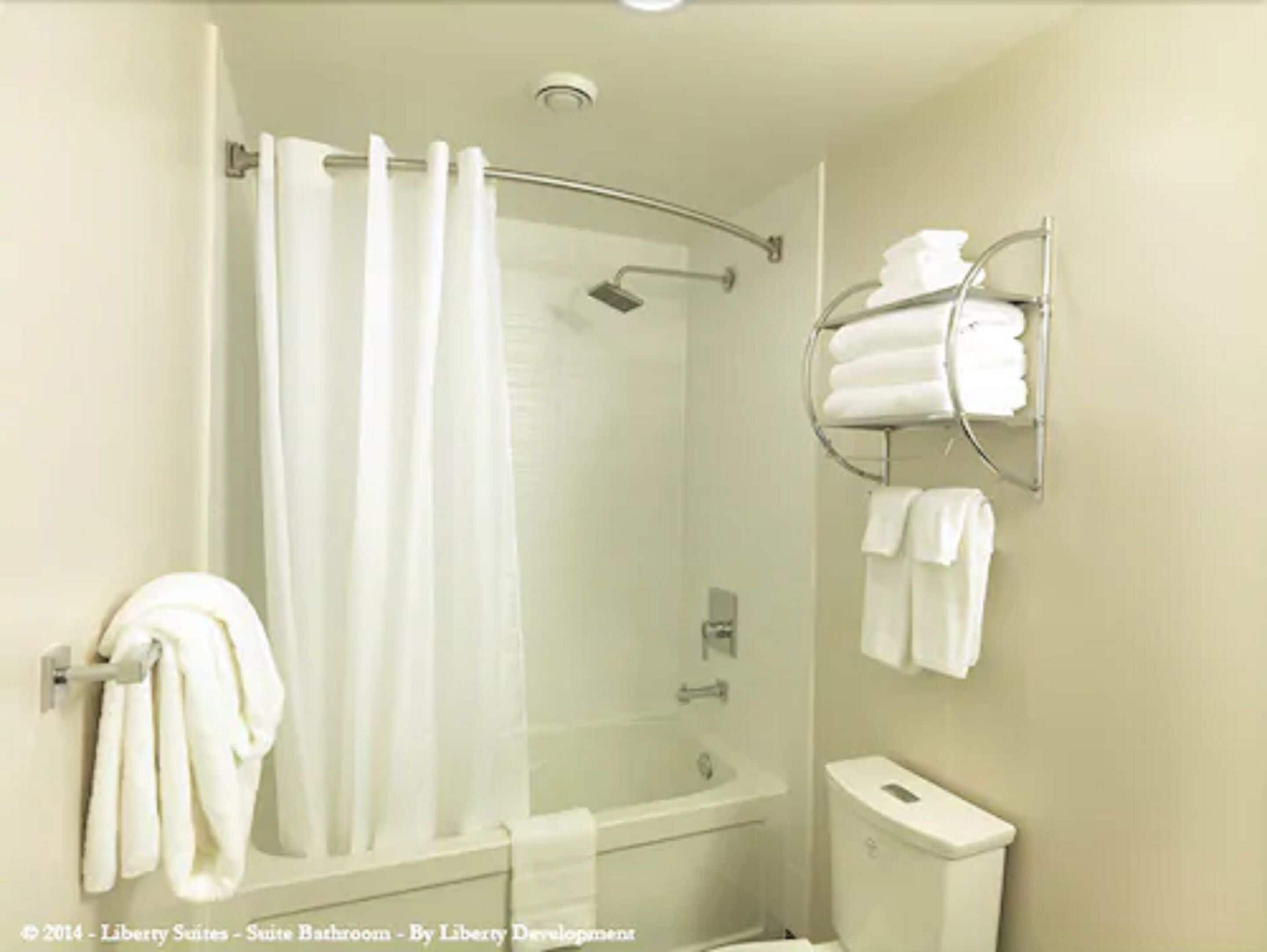 Une salle de bain équipée d’une douche, de toilettes et d’un porte-serviettes avec des serviettes.
